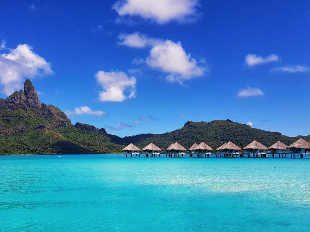Bungalows sur pilotis à Bora Bora, offrant une vue panoramique sur le lagon turquoise et un accès privilégié aux eaux cristallines, pour un séjour idyllique au cœur de la Polynésie.