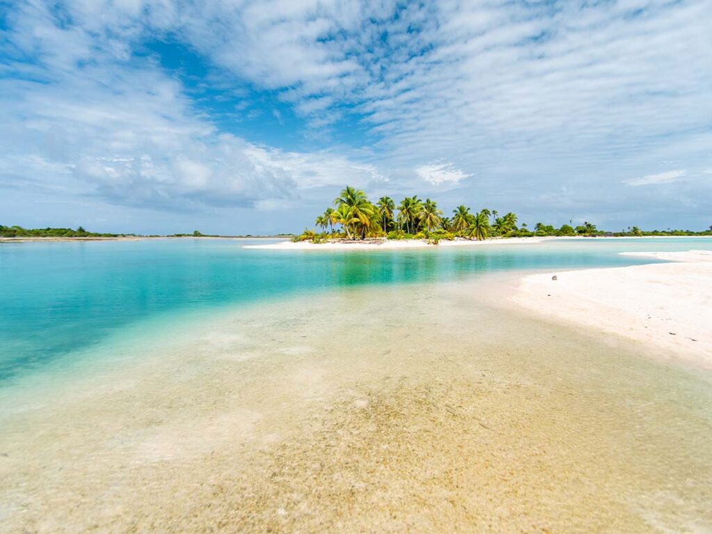 Lagon turquoise et motu paradisiaques à Tikehau en Polynésie française, offrant des plages de sable rose et des eaux cristallines d’une beauté incomparable.