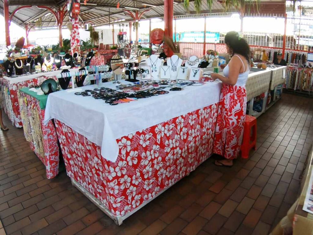 Intérieur du marché de Papeete à Tahiti, avec des stands colorés proposant vanille, poissons frais, fleurs tropicales et souvenirs artisanaux.