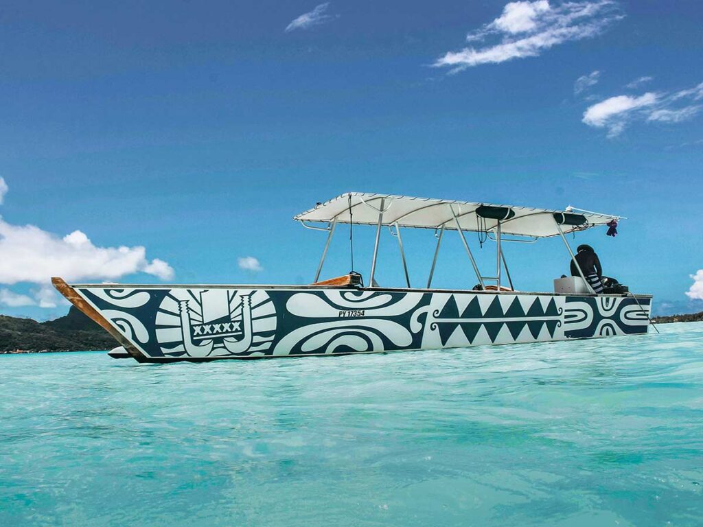 Pirogue traditionnelle à Bora Bora glissant sur les eaux cristallines du lagon, offrant un aperçu de la culture polynésienne dans un décor naturel spectaculaire
