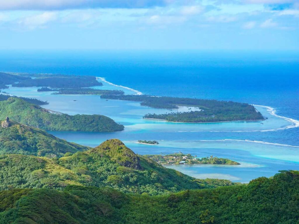Vue panoramique sur le lagon turquoise de Huahine lors d'une randonnée à travers la végétation luxuriante de l'île.