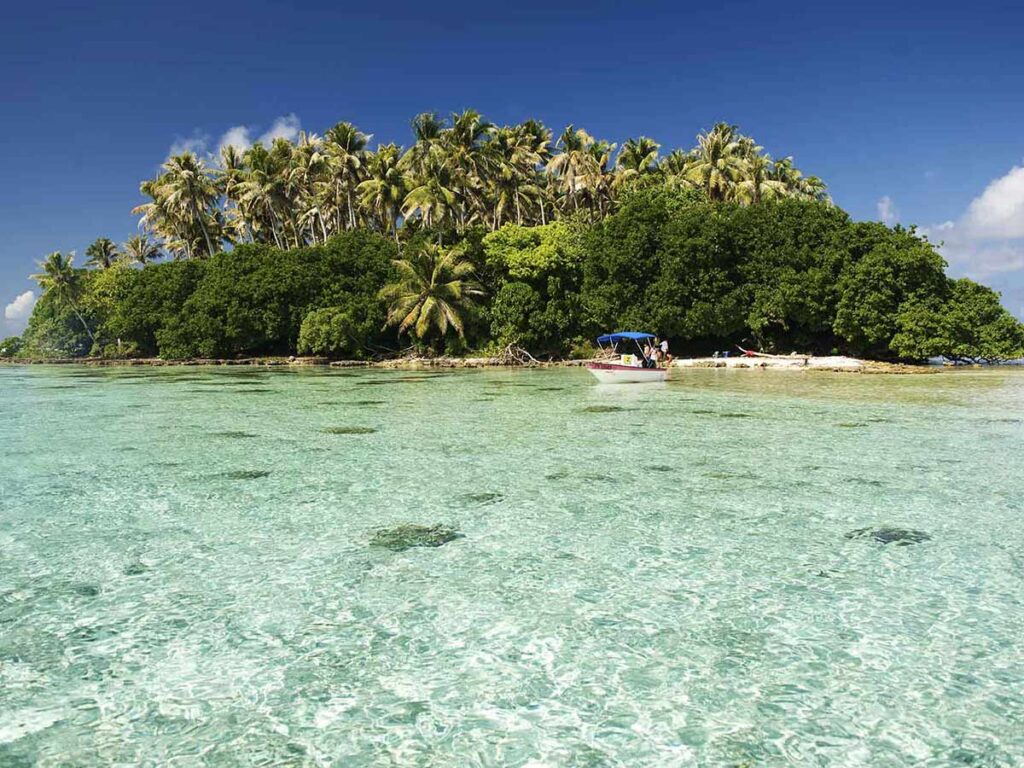 Motu idyllique près de Raiatea avec plage de sable blanc, cocotiers et eaux turquoise cristallines.