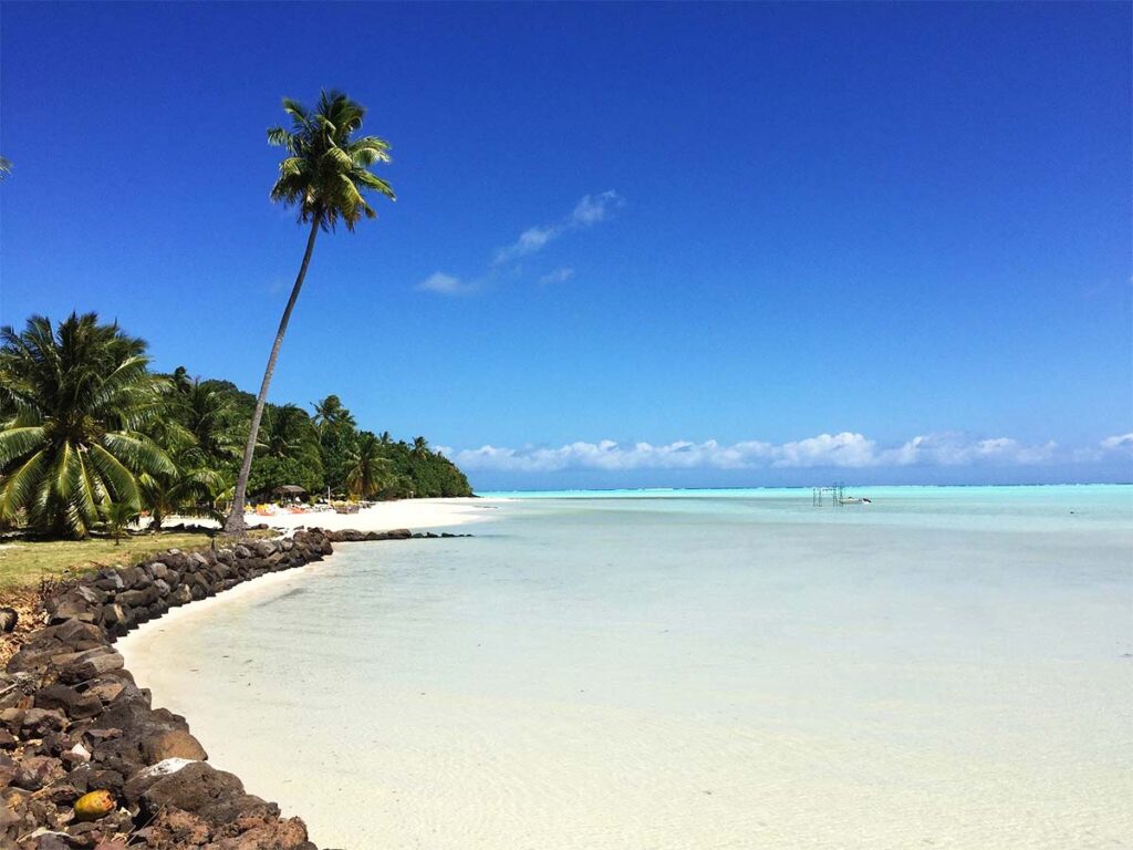 Plage de Tereia à Maupiti avec sable blanc, eau turquoise peu profonde et horizon paisible.