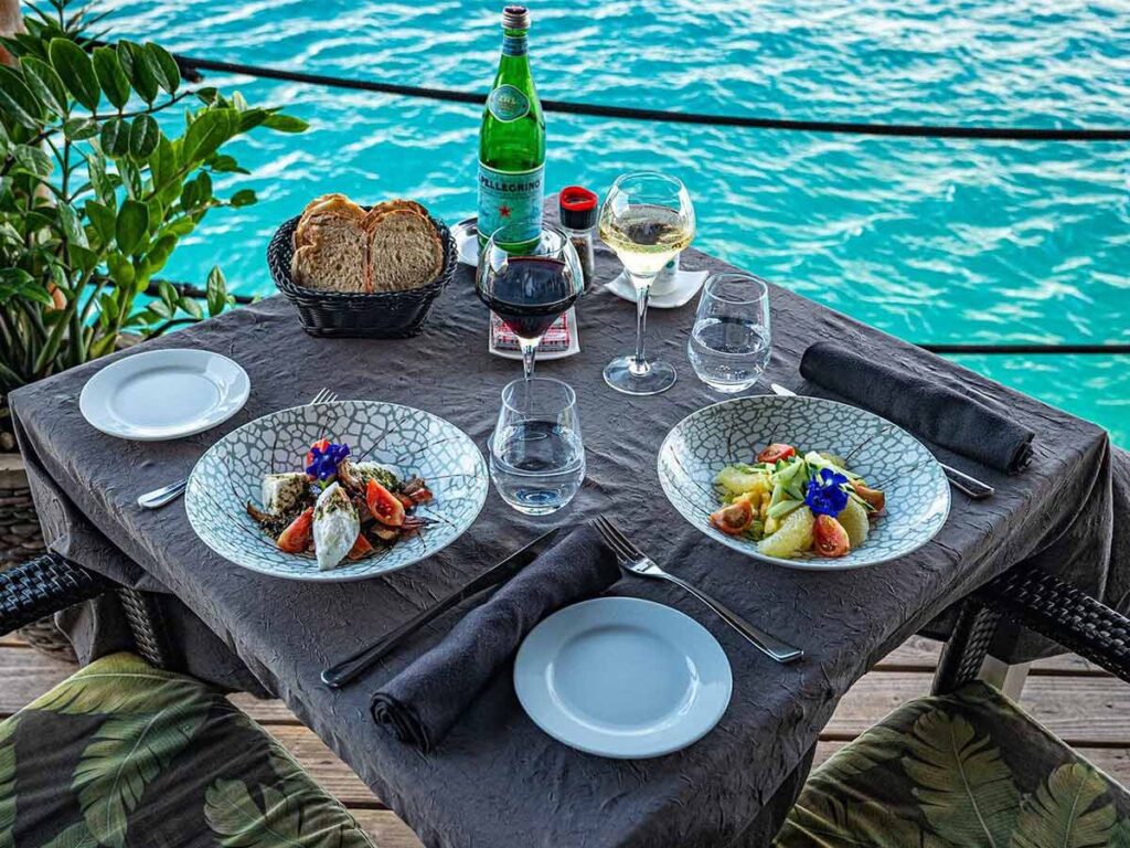 Deux plats servis sur une table au restaurant St James Bora Bora, avec vue sur le lagon.
