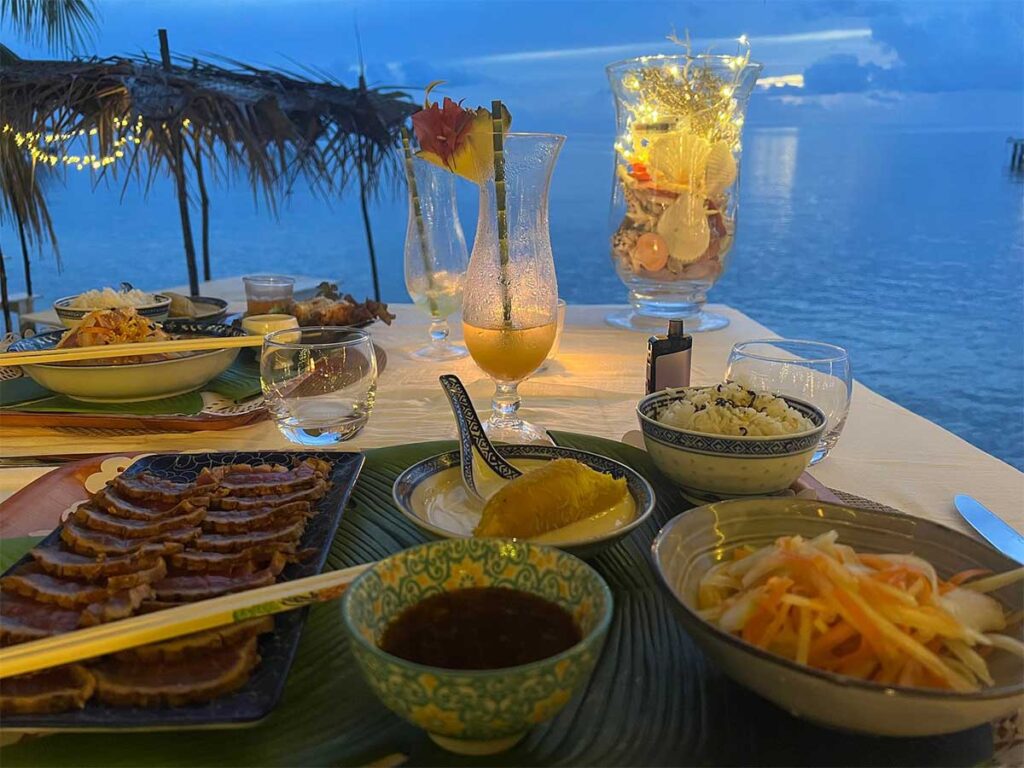 Table dressée au restaurant Fish & Blue à Raiatea, avec vue sur le lagon après le coucher du soleil.