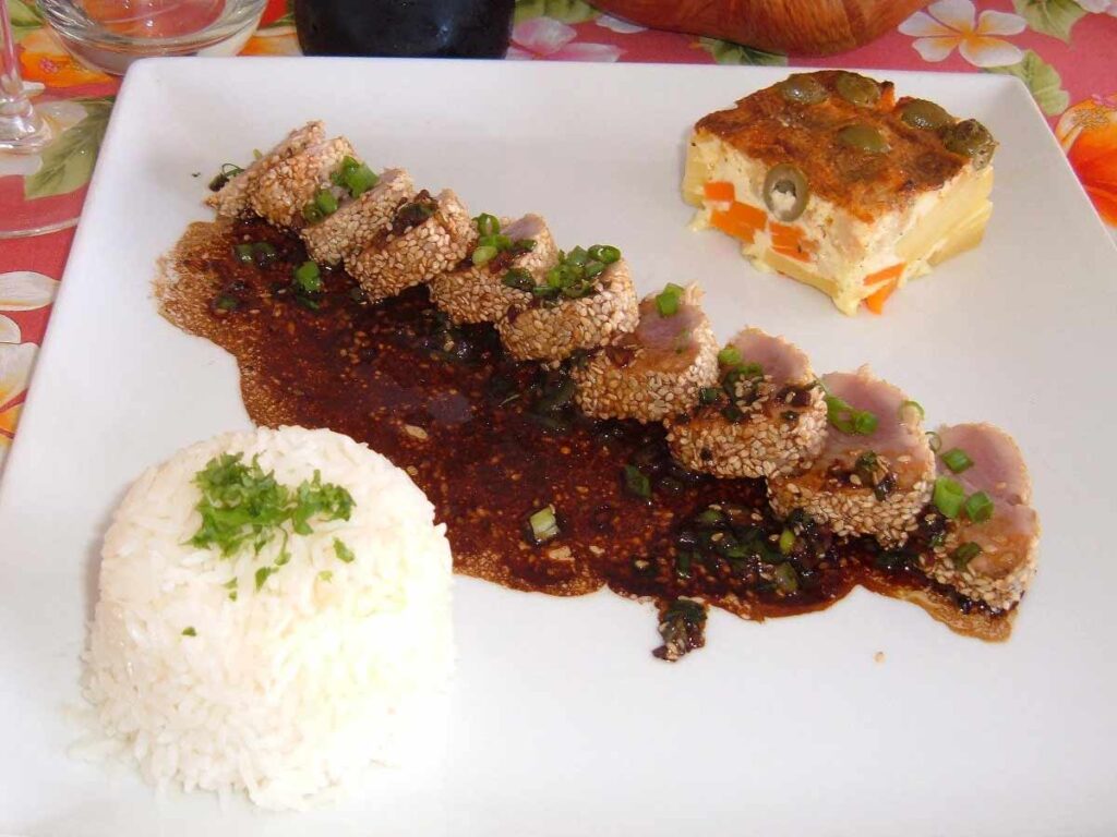 Assiette de spécialités polynésiennes servie au restaurant Tahaa Maitai, avec vue sur le lagon à Tahaa.