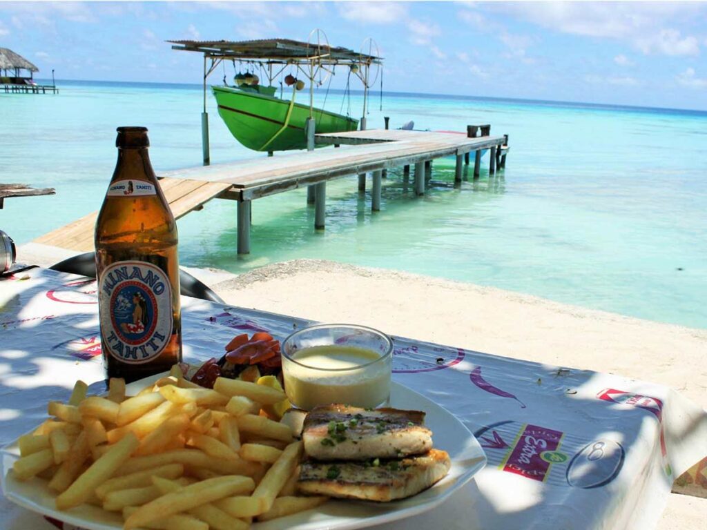 Assiette de cuisine polynésienne servie au Snack Chez Elda Aux Port à Fakarava, avec vue sur le lagon.