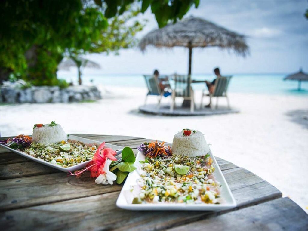 Assiette de spécialités polynésiennes servie sur le sable au Snack du Requin Dormeur, en bord de lagon à Fakarava.