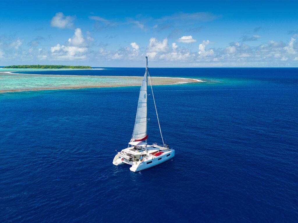 Catamaran de Poe Charter naviguant dans les eaux turquoise de Tetiaroa, offrant une expérience unique de croisière en Polynésie française.
