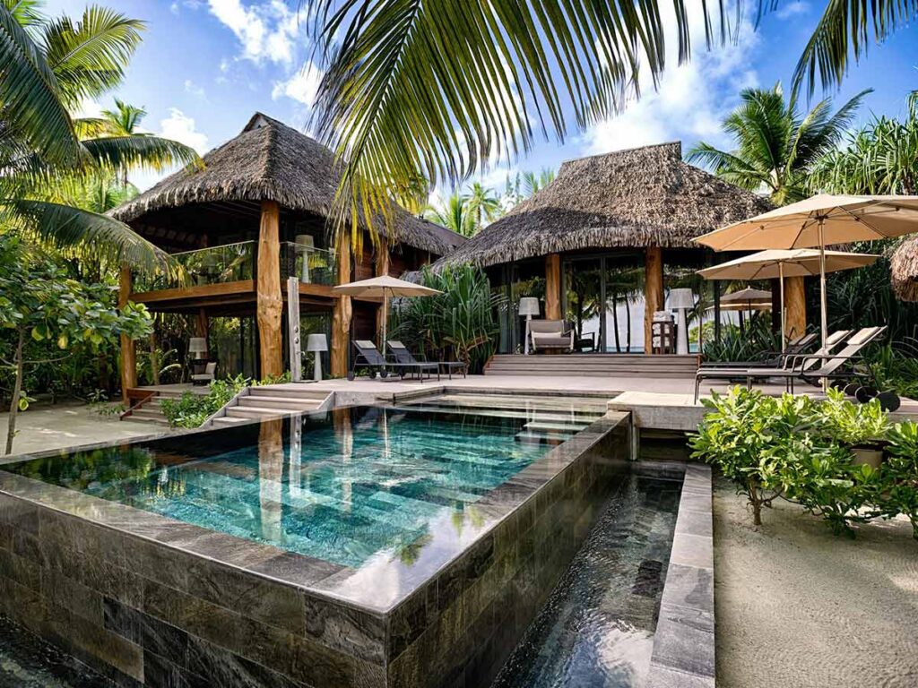 Villa de luxe avec piscine privée entourée de palmiers au Brando, hôtel exclusif sur l'atoll de Tetiaroa en Polynésie française.